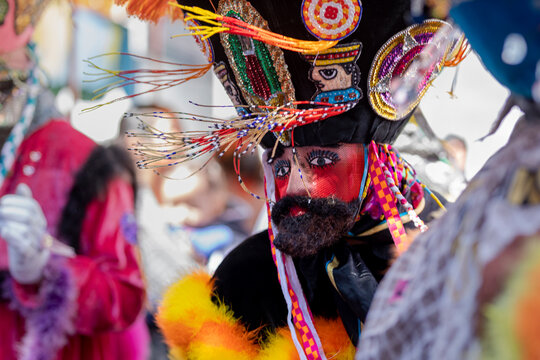 A person in a chinelo costume dancing effusively at a carnival in the State of Mexico