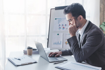 Fototapeta premium Finance and investment concept, Businessman feel stress while colleagues discussing new investment plan by financial graph data on office table with laptop and digital tablet.