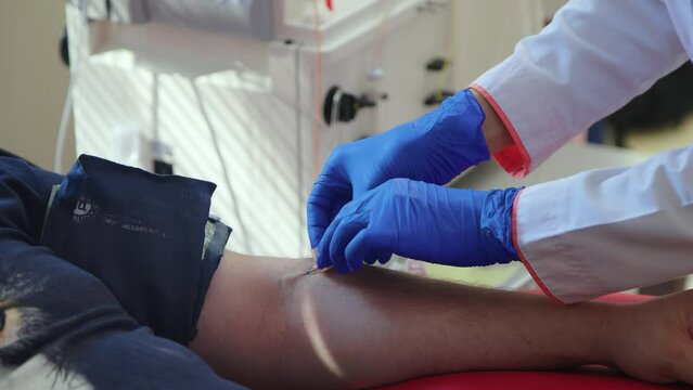 Taking blood from a patient. Doctor makes phlebotomy to collect red blood cells for donation.