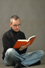 person reads a book sitting cross-legged