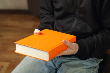 a person is holding an orange book in front of him