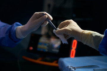 Surgeon in the operating room passesl instrument to colleague