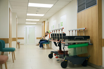 People in casual clothes are sitting in a hospital corridor