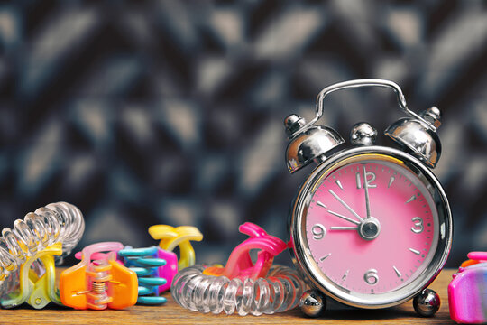 Girls fancy alarm clock and a hair equipment on the bedroom table. Interior and fashion backgrounds