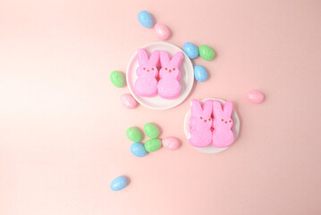 pink and blue easter eggs masmellow bunnies on a pink background 