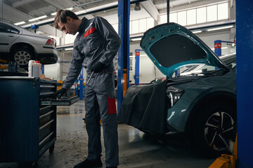 Male chooses tools for car repair in workshop