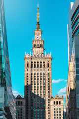 Fototapeta na wymiar The clock tower of the Palace of Culture and Science,a historical symbol of Warsaw in the Empire style, surrounded by modern buildings.A combination of styles in the architectural appearance.Vertical