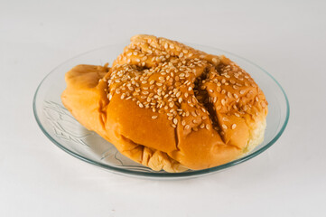 bread sprinkled with sesame seeds is served on a small plate isolated on a white background