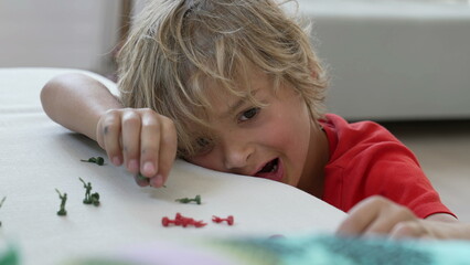 Obraz na płótnie Canvas Close up child face playing with toy soldiers. One imaginative small boy plays with miniature combat figurines