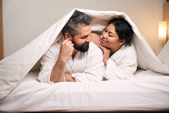 Romantic couple in bathrobes resting in hotel room