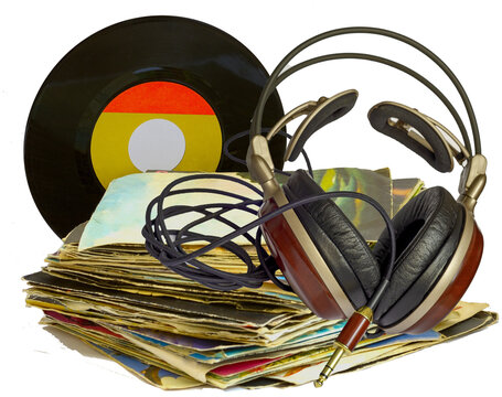 Stack of old 45 RPM vinyl records and headphones with wooden earphones