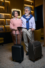 Traveling elderly couple in the hotel lobby waiting for registration