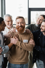 Positive multiethnic people hugging man during alcoholics group therapy in rehab center.