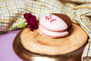 Obraz na płótnie Canvas Whoopie Pie on a round plate view from a top. A lilac carnation flower adorns a still life with a sweet American cookie. Round trendy details in food photo. Soft biscuits with a creamy layer flatly.
