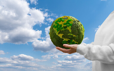 Woman holds a green planet Earth on a background of blue sky. Symbol of sustainable development and...