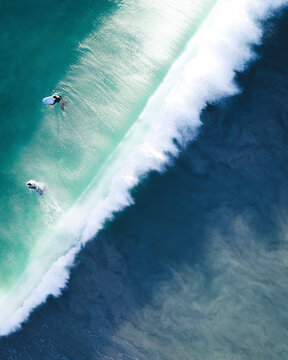 Aerial view of people doing surf on the waves along the shore in City Beach, Western Australia, Australia.