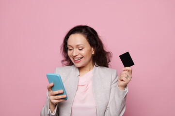 Naklejka premium Pretty woman using smartphone, making online payments via mobile apps and internet banking, shopping online, ordering food, transferring money, isolated over pink background, People. Banking concept