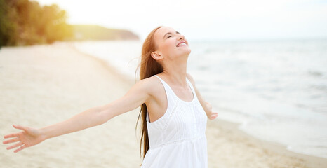 Happy smiling woman in free happiness bliss on ocean beach standing with open hands. Portrait of a...