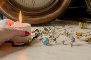 female hand holds a burning candle on a light natural background. pagan wiccan, slavic traditions....