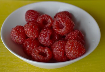 ripe raspberries in a small white cup