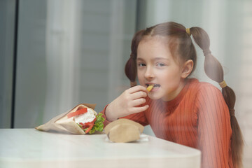 Cute little girl with ponytails eating souvlaki for lunch in Greek restaurant. Adroable white kid...