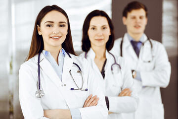 Fototapeta premium Group of young professional doctors is standing as a team with arms crossed in a hospital office and is ready to help patients.
