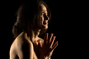 Obraz premium Silhouette of young unhappy prying woman on black background