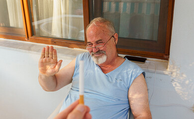 Elderly man refusing smoking cigarette offer at home. Quit smoking concept idea photo. 
