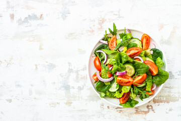 Fresh green salad with leaves and vegetables. Arugula, spinach, tomatoes and onion.