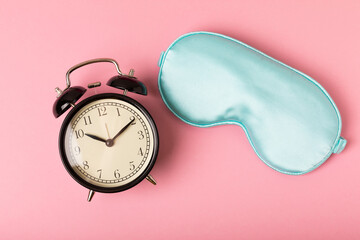 Fototapeta Sleep mask and alarm clock on a pink background.LET'S RAISE. The concept of rest, sleep quality, good night, insomnia, relaxation. Place for text. obraz