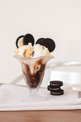 Cup of ice cream with chocolate cookies on a wooden table.
