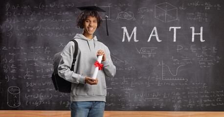 African american male student holding a diploma in front of a blackboard with math formulas
