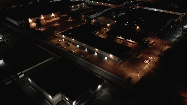 A large commercial warehouse building is shown from an overhead view at night. This business park is illuminated mostly with orange sodium vapor lights.