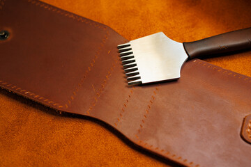 The process of production of leather goods. Materials and tools for leather production. Beautiful brown leather products and tools for needlework.