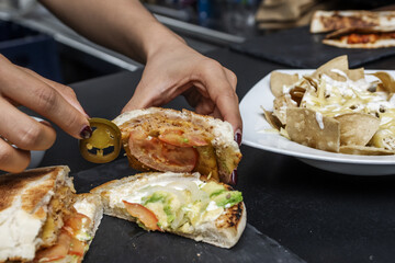 A female cook implementing jalapeno slices into an onion burger