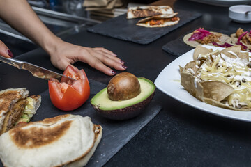 A cook chopping a tomato to prepare guacamole and other Mexican food recipes