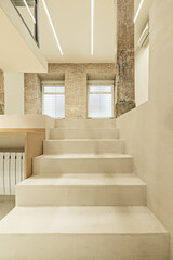 Polished white concrete stairs of a loft with vintage wooden columns and beams