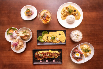 Still life with Peruvian food dishes with huancaina potatoes, ceviches, chicken stew, lomo saltado with quail egg