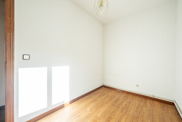 A room with lsio white painted walls, oak slat parquet flooring, outdoor heating ducts and a ceiling lamp