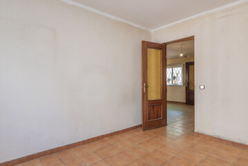 Fototapeta na wymiar A small room with gotele walls and poorly painted white, brown stoneware floors and a sapele wood door with glass