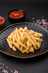 Delicious crispy french fries with salt and spices on a dark concrete background