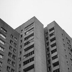 Czarno-białe zdjęcie bloku mieszkalnego z wielkiej płyty na tle czystego nieba 