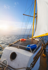 Old schooner sailing the sea at sunset.