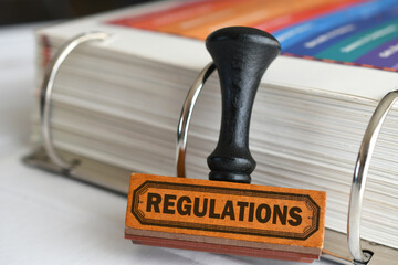 A regulations rubber stamp against handbook of rules and bylaws. 