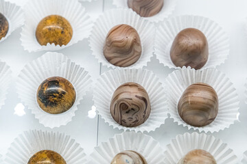 A chocolate confectionary and bakery glass display of handmade individual truffles in a variety of colors and flavors with white paper wrappers