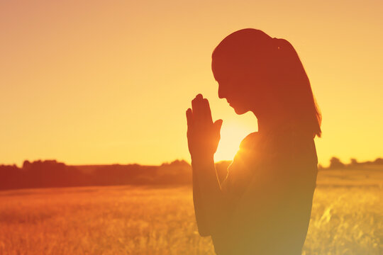 Woman saying a prayer out in the nature sunlight 