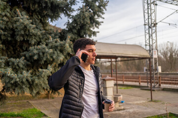 Fototapeta na wymiar Young man standing outside and talking on the phone 