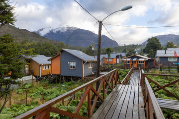 Fototapeta na wymiar Small colorful houses and nalca plants along the wooden paths of Tortel, Patagonia, Chile
