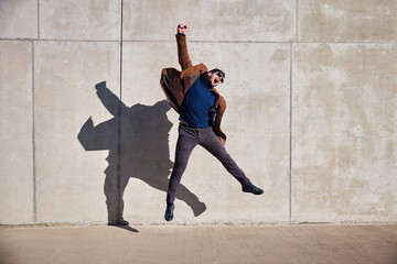 Victory concept. Joyful man jumping against concrete wall celebrating success