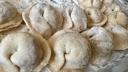  Sculpts dumplings and puts them on a wooden table, there are a lot of them, they are appetizing in flour and waiting to be cooked Each dumpling is full of meat, they are round and neatly handmade